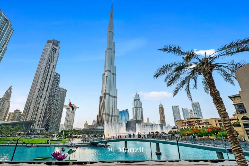 een uitzicht op de skyline van Dubai met een palmboom bij Manzil - Luxury 3BR Villa w/ maid room, Full Burj & Fountain view in Dubai