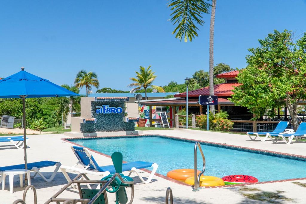 a swimming pool with chairs and an umbrella at Parador El Faro in Aguadilla