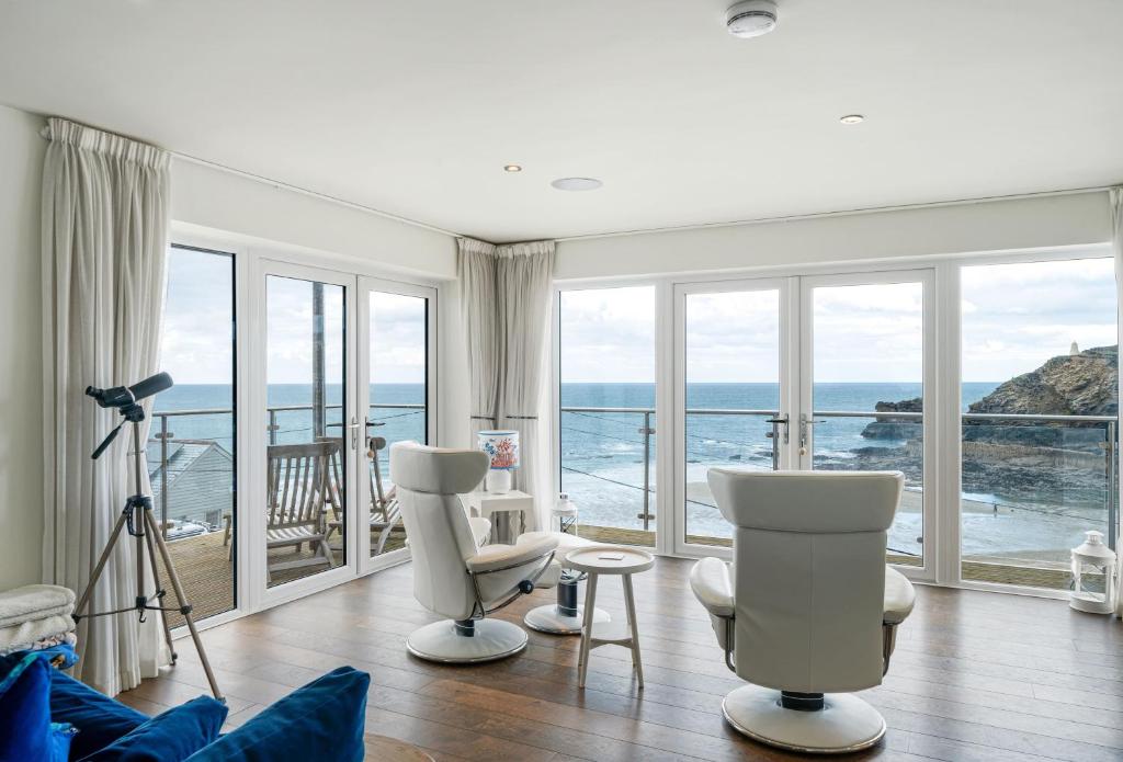 una sala de estar con sillas blancas y vistas al océano. en The Lookout, en Portreath