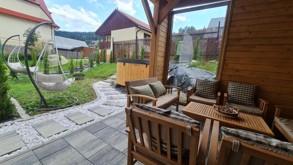 a patio with a porch with a swing and a chair at Szumią Płaziny in Muszyna