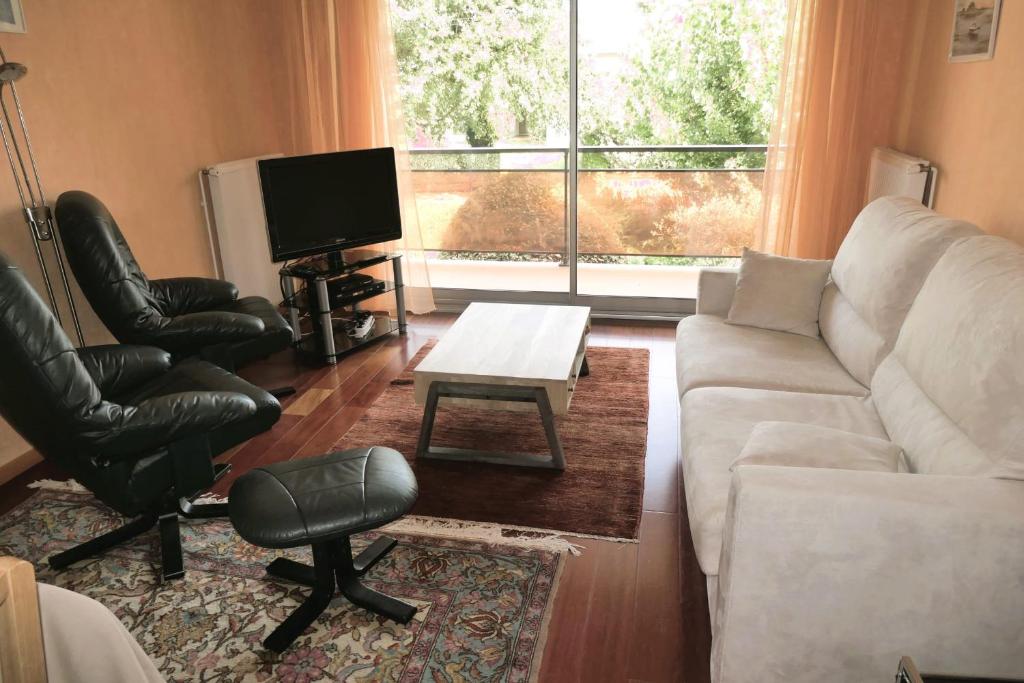 a living room with a white couch and a tv at Cosy cocoon with terrace near the sea in Arcachon