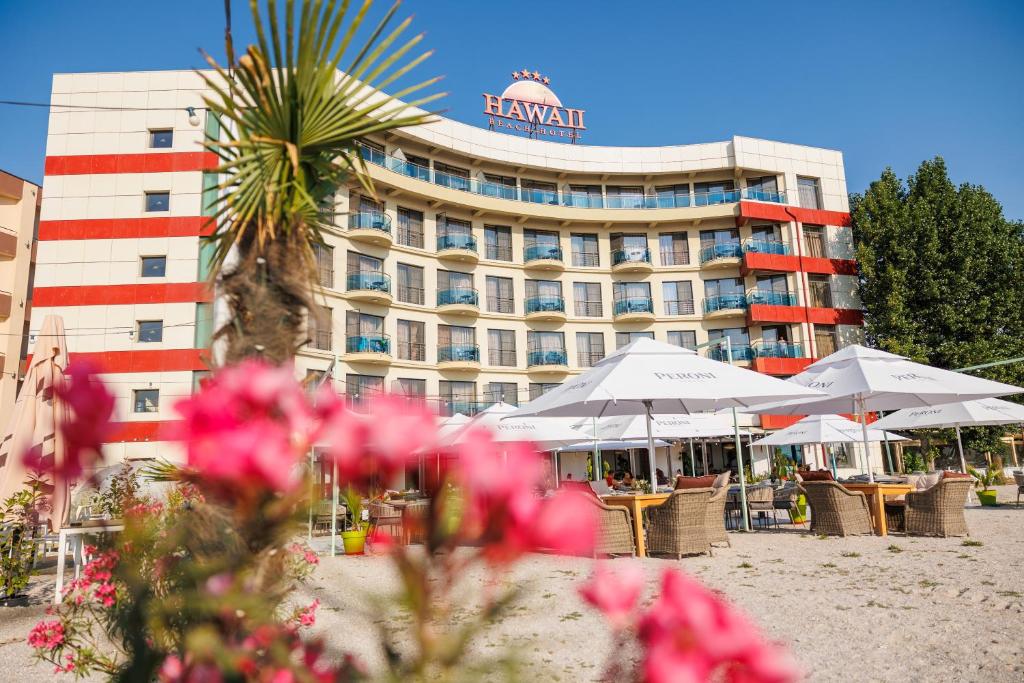 a hotel with tables and chairs in front of a building at Hotel Hawaii in Mamaia