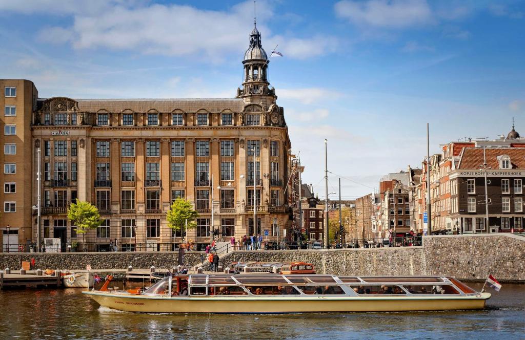 twee boten in het water voor een gebouw bij art'otel amsterdam, Powered by Radisson Hotels in Amsterdam