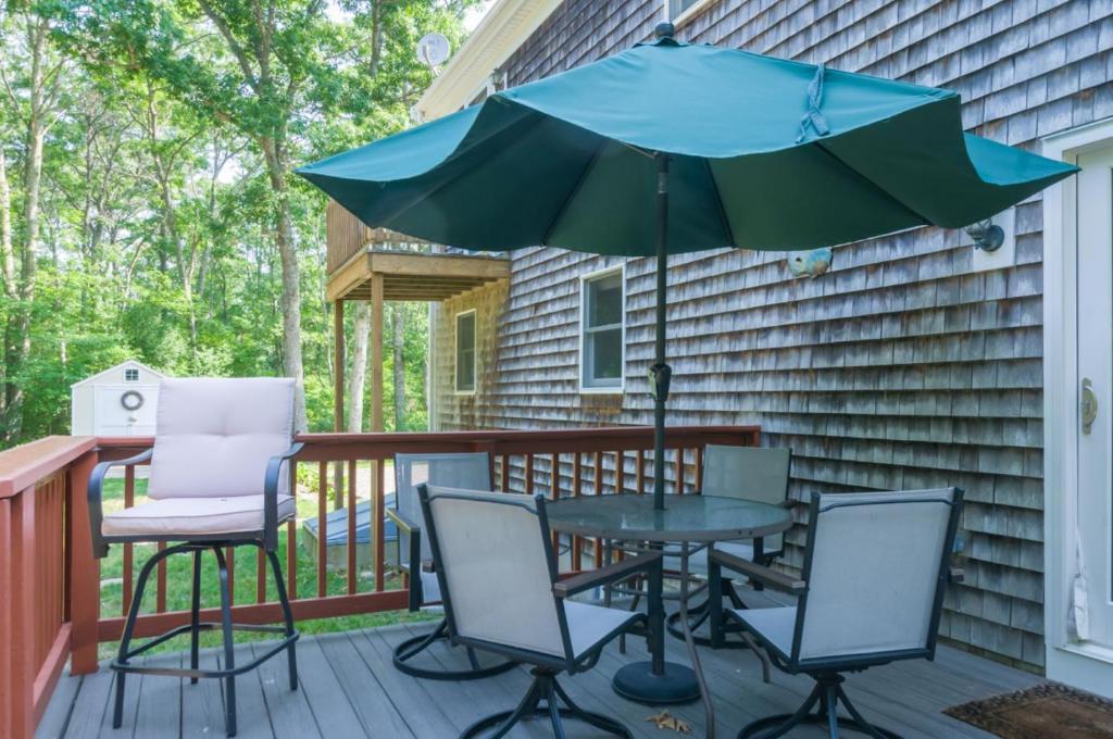 Un patio con una mesa y sillas y una sombrilla. en 132 Hooppole Road Mashpee Indra Cottage, en Mashpee