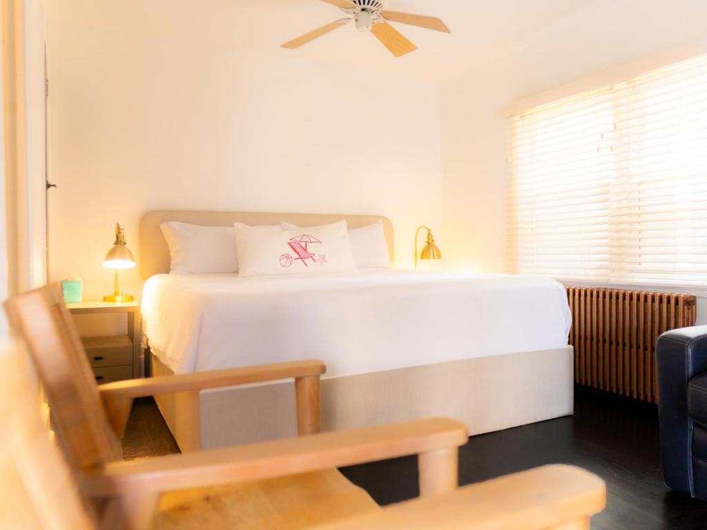 a bedroom with a white bed and a chair at Beachliner Hotel in Ocean Grove