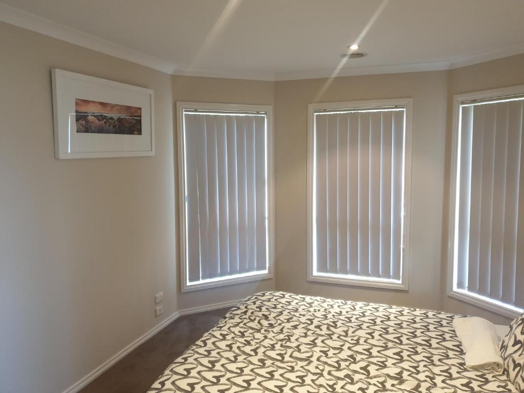 a bedroom with two large windows and a bed at Pacific Werribee Home 25 Min CBD Airport in Werribee