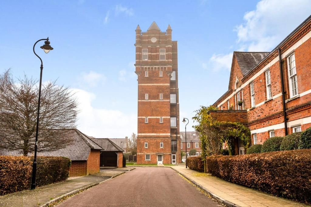 an empty street in front of a brick building with a clock tower at Amazing converted water tower! in Coulsdon