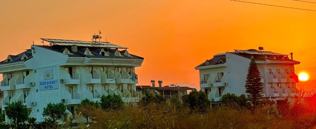 two buildings with the sunset in the background at Colaklı Sunset Otel in Side