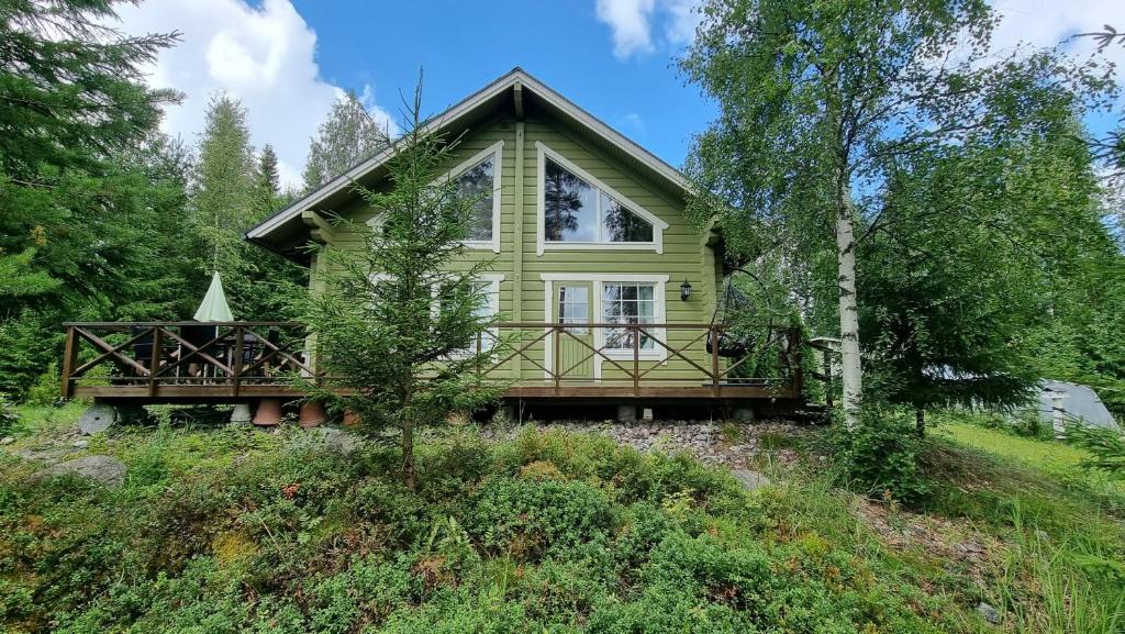 ein grünes Haus mit einer großen Terrasse auf einem Hügel in der Unterkunft Villa Helmi in Jämsä