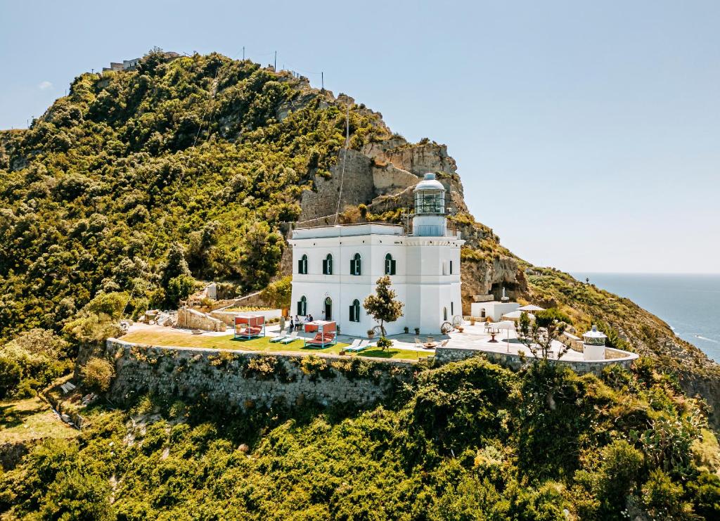 una casa en una montaña junto al océano en Faro Punta Imperatore en Isquia