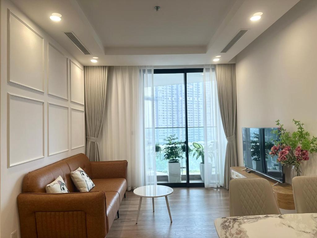 ein Wohnzimmer mit einem Sofa und einem großen Fenster in der Unterkunft Cakey House-Căn hộ sân vườn 3PN2WC 106m2 in Hanoi