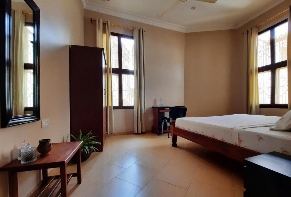 a bedroom with a bed and a table and windows at Modern apartment in Stone Town in Stone Town