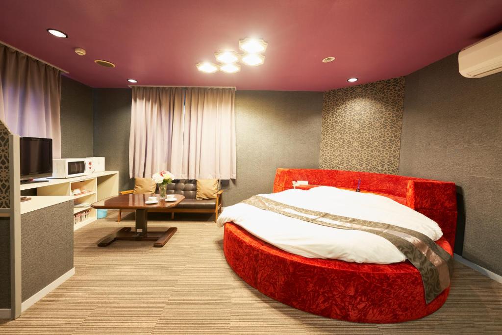 a bedroom with a large red bed and a table at ホテル　モモ 