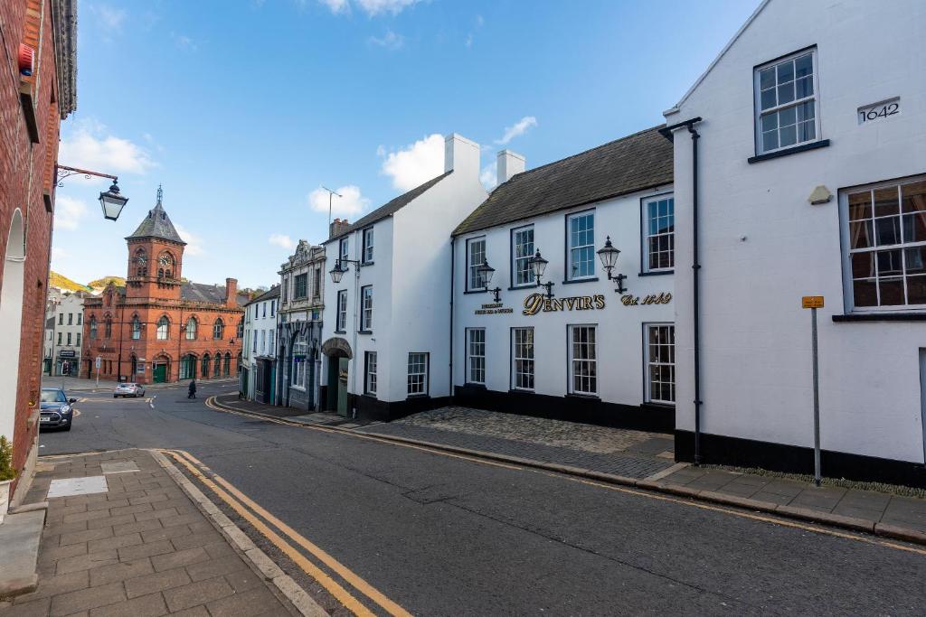 una via cittadina con edifici bianchi e una torre dell'orologio di Denvir's Coaching Inn a Downpatrick