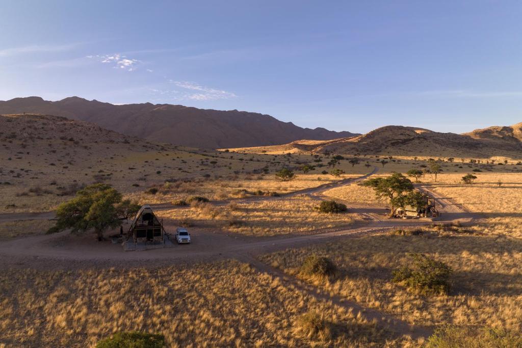 Una vista del desierto con una casa y una carretera en Camp Gecko - PRIVATE NATURE RESERVE; TENTED CAMP AND CAMPSITE, en Solitaire