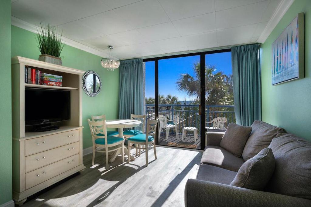 a living room with a couch and a television and a table at Oceanfront Condo with Amazing Outdoor Amenities in Myrtle Beach