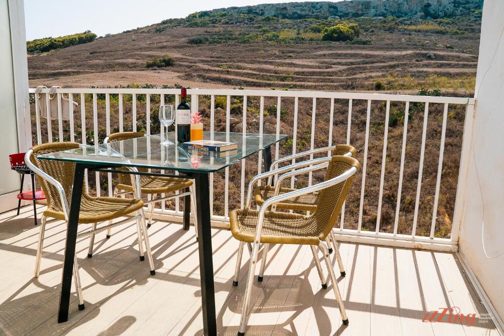 un tavolo in vetro e sedie su un balcone con vista di Country views by the sea. Holiday time in Gozo. a Żebbuġ