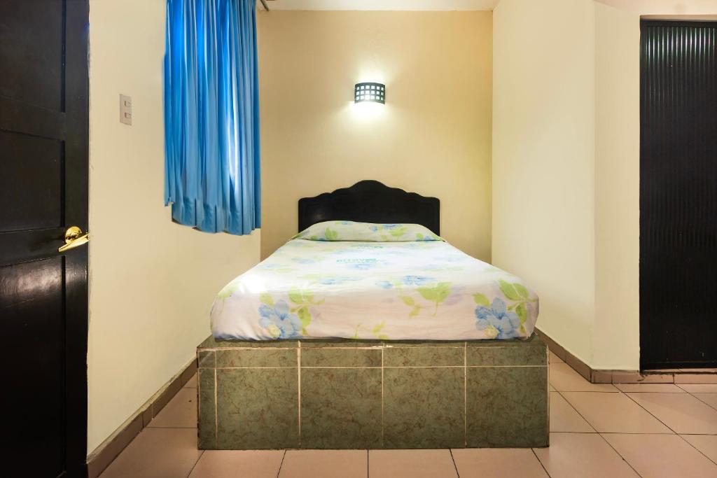 Cama pequeña en habitación con cortinas azules en OYO Hotel San Martin, en Veracruz