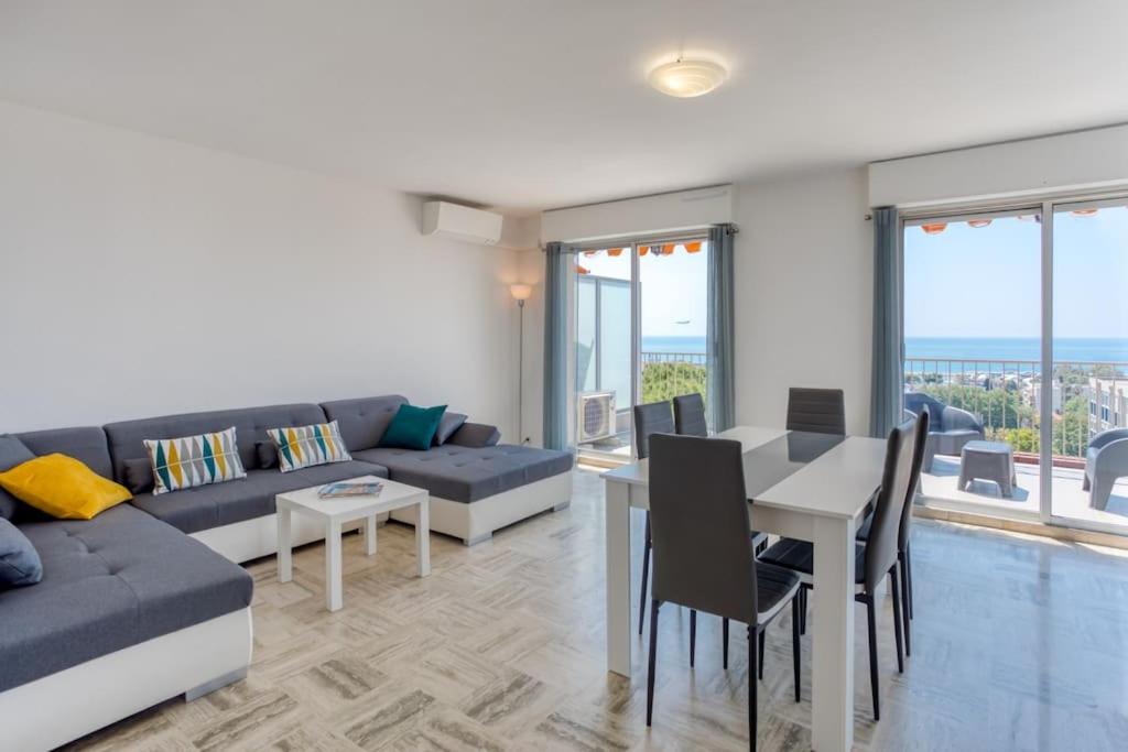 ein Wohnzimmer mit einem Sofa und einem Tisch mit Stühlen in der Unterkunft L43 Suite Maurice sea view 6Pax/Terrace,Parking,AC in Saint-Laurent-du-Var