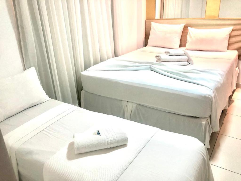 three beds in a hotel room with towels on them at Hotel Pousada Kairos Manaira in João Pessoa