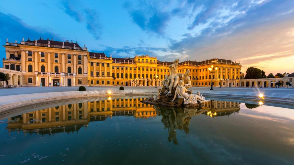 a large yellow building with a fountain in front of it at Schönbrunn Serenity Luxurious Ruby Apartment with Palace Views in Vienna