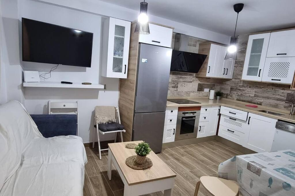 cocina con armarios blancos y sala de estar. en Piso amplio completo en Almería para 9 personas, en Almería