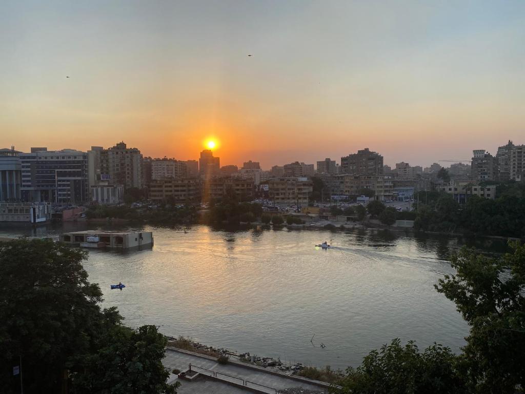un coucher de soleil sur une rivière dans une ville avec des bateaux dans l'établissement Nile View Apartment in Zamalek Stays, au Caire