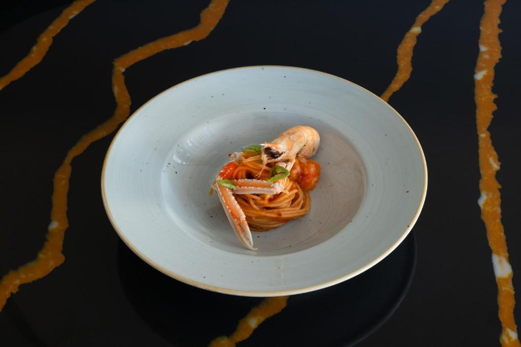 a white plate with pasta and shrimp on a table at Savoy Beach Hotel & Thermal Spa in Bibione