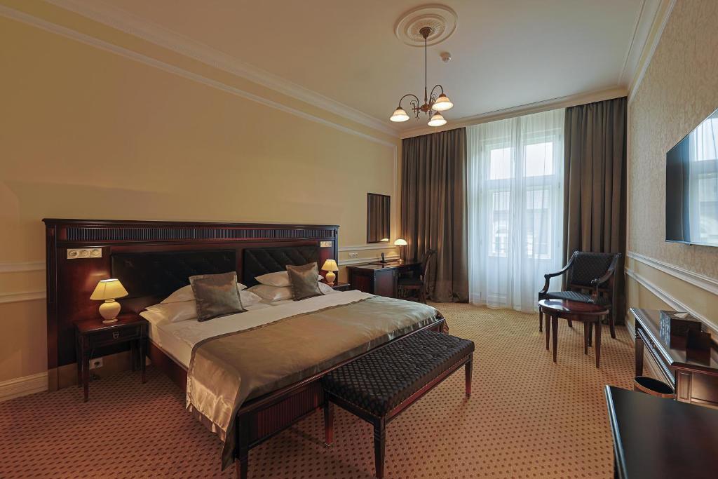 ein großes Schlafzimmer mit einem großen Bett und einem Stuhl in der Unterkunft Luxury Spa Hotel Olympic Palace in Karlsbad