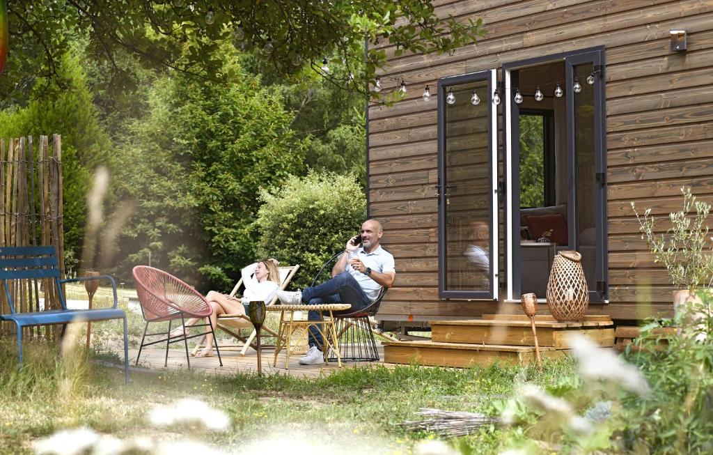 dos personas sentadas en sillas fuera de una cabaña en La tiny house de la Blandinière en Vertou