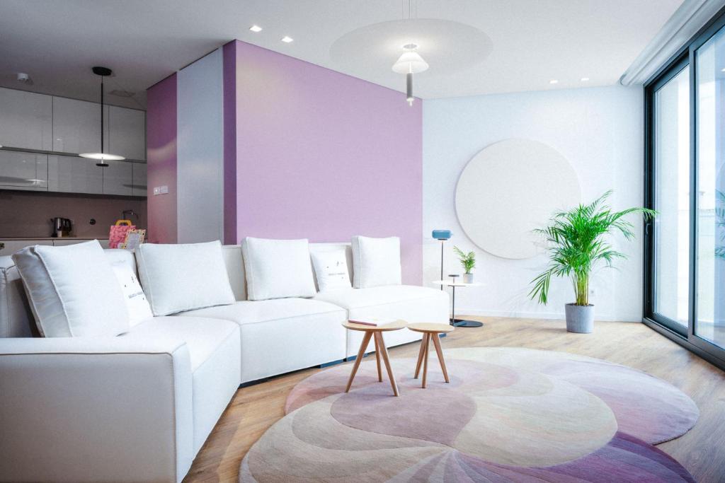 een woonkamer met een witte bank en een paarse muur bij Design-Apartment Olhão by Sisters of Paradise in Olhão