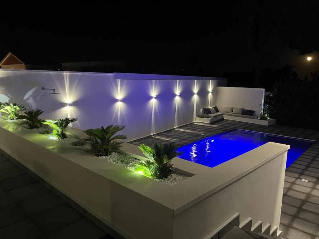 - une piscine dans une arrière-cour éclairée la nuit dans l'établissement Villa Giuliana Luxury Home: piscina, solarium, barbecue. A pochi passi dal mare, à Fontane Bianche