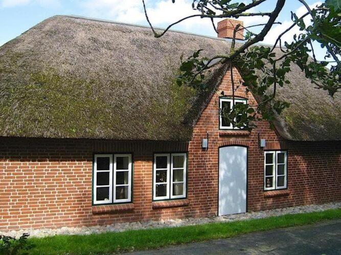 a brick house with a grass roof with a door at Holiday home in Westerhever with a fireplace and a beautiful garden in Westerhever
