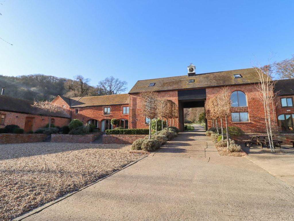 un gran edificio de ladrillo con un camino delante de él en The Stables en Ledbury