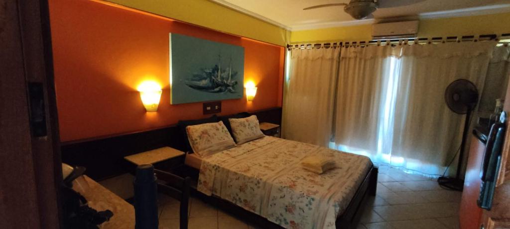 Schlafzimmer mit einem Bett, einem Tisch und einem Fenster in der Unterkunft Flat para ate 4 pessoas - Frente a Praia dos Anjos in Arraial do Cabo