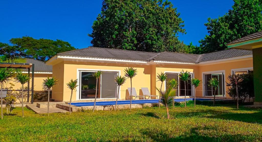 a yellow house with palm trees in the yard at Amber Villa Malindi in Malindi