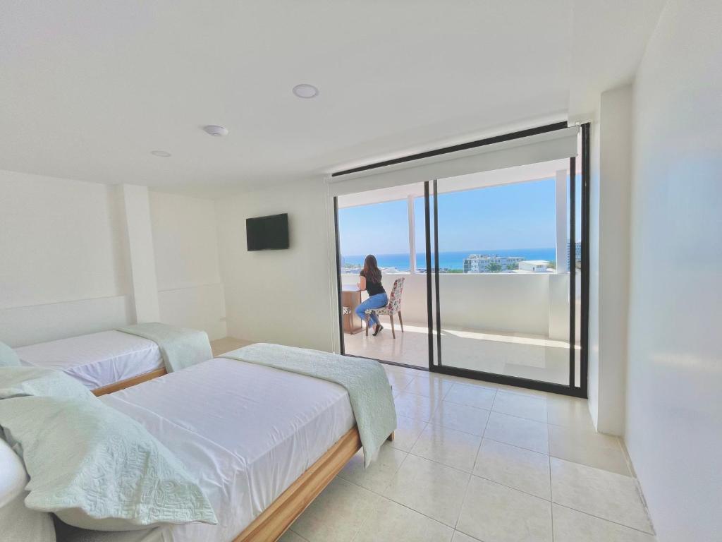 ein Schlafzimmer mit 2 Betten und eine Frau auf einem Stuhl in der Unterkunft Apartamento con hermosa vista in Manta