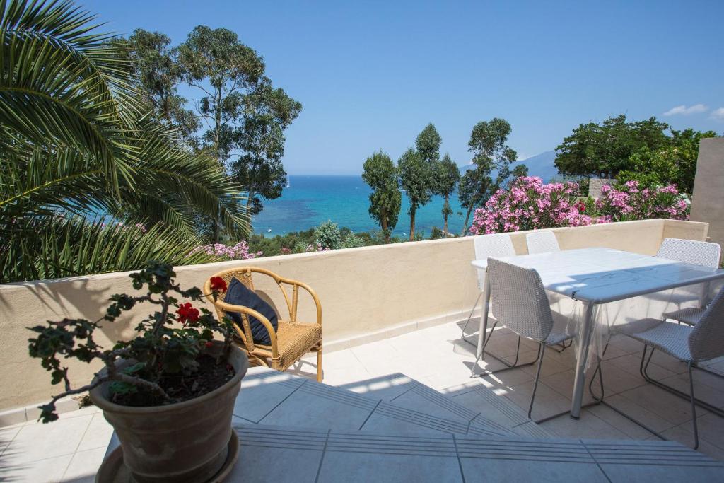 un patio con tavolo, sedie e vista sull'oceano di APPARTEMENT TERRASSE La Citadelle Appartements Saint Florent a Saint-Florent
