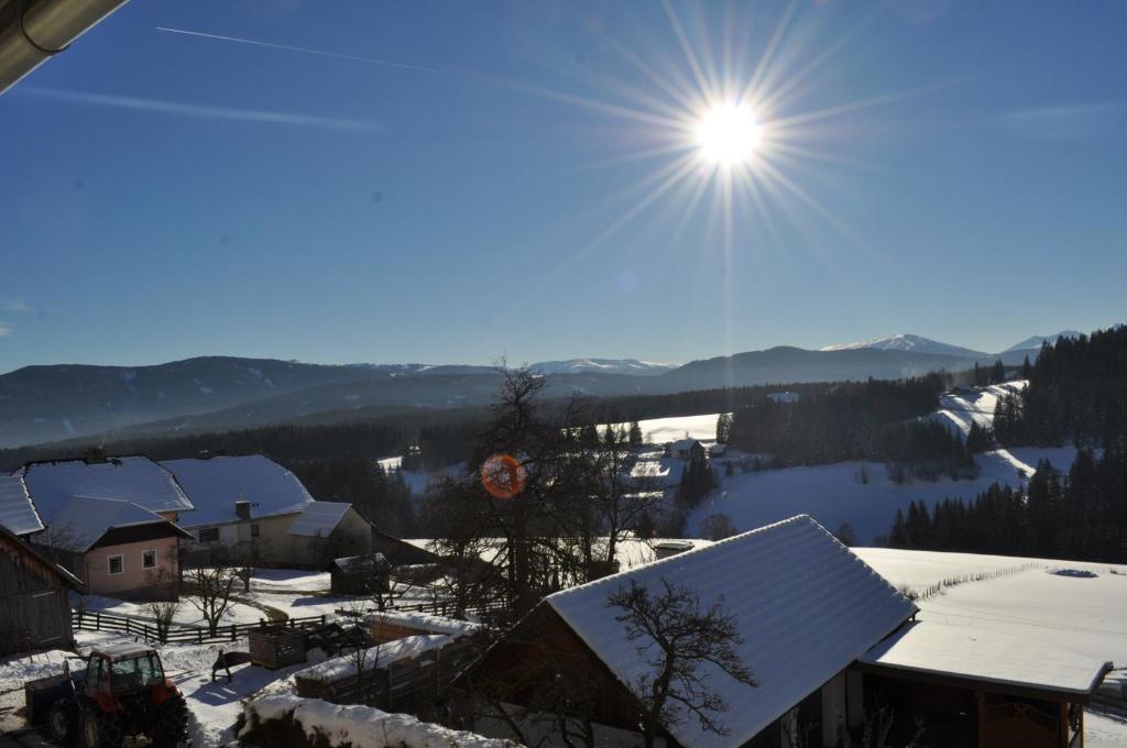 uma aldeia coberta de neve com o sol no céu em Haashof em Vordergöriach