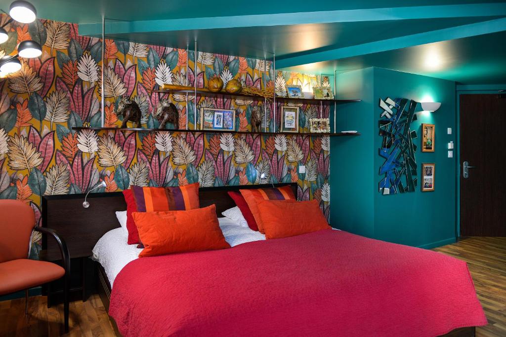 a bedroom with a red bed and a colorful wall at Logis Hôtels Le Saint Georges in Vendôme