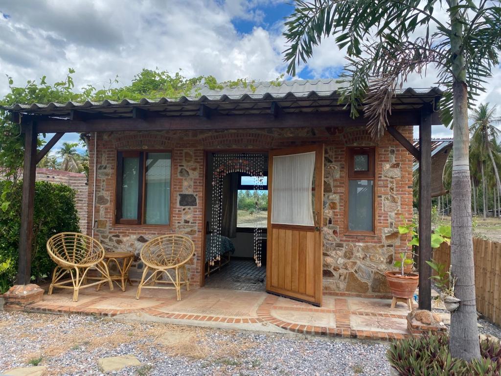 une maison en briques avec une porte et des chaises en bois dans l'établissement Driftwood and Jolie cottages, à Sam Roi Yot