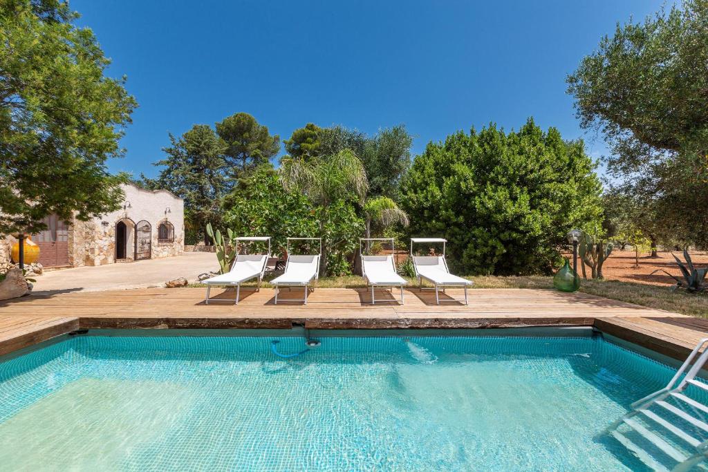 a swimming pool with lounge chairs and a group ofitures at Trullo Kalia by BarbarHouse in San Michele Salentino