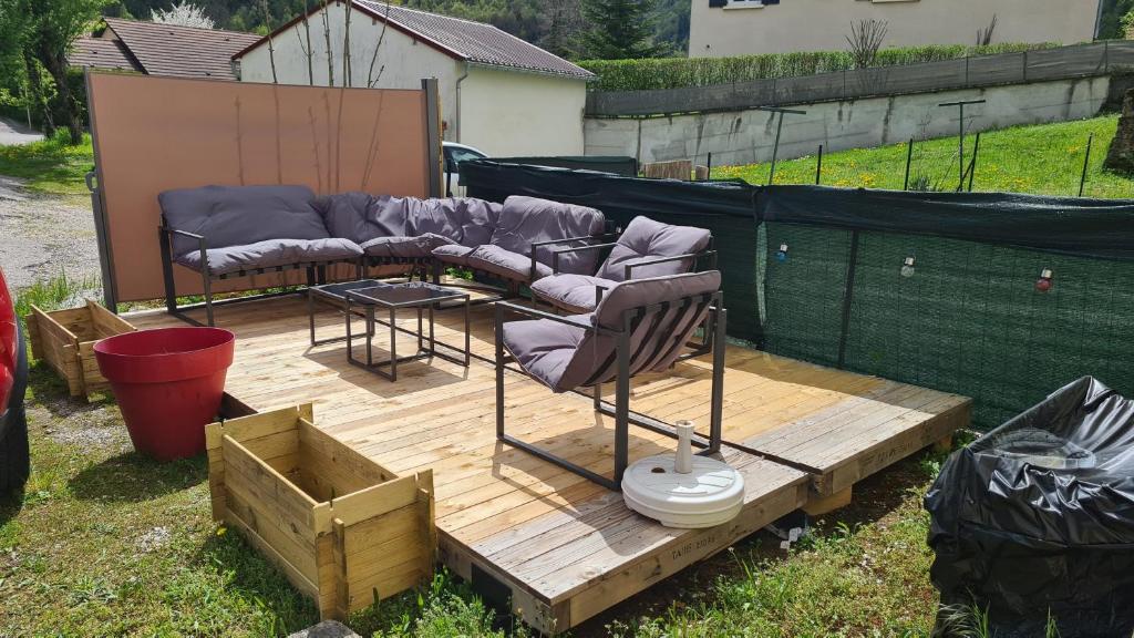 une terrasse en bois avec un canapé et des chaises. dans l'établissement Appartement au cœur du Haut-Jura, à Villard-Saint-Sauveur