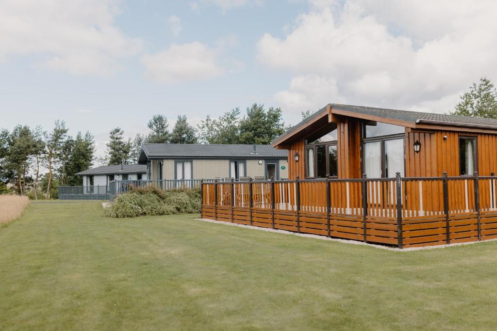 a wooden house with a large yard in front of it at Linwater Holiday Park in Newbridge