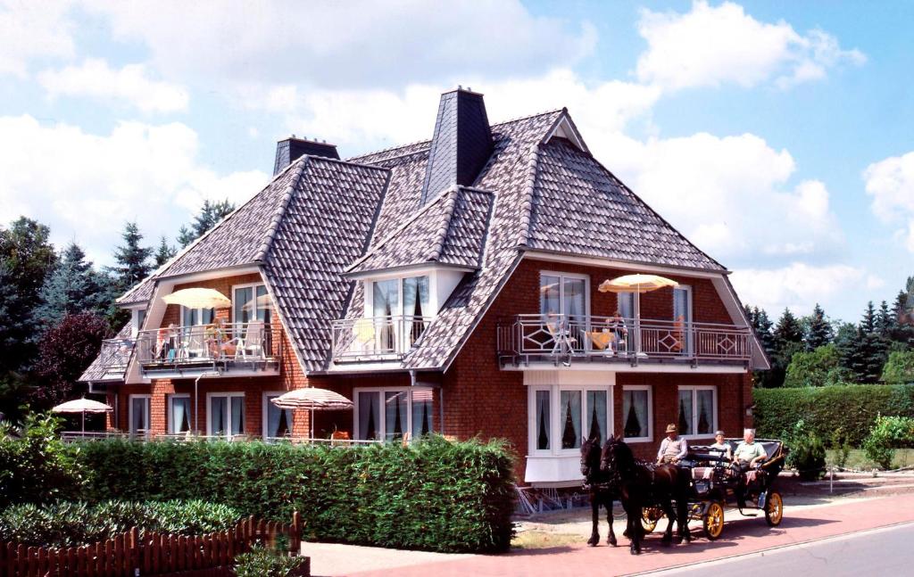 un carruaje tirado por caballos frente a una casa grande en Landhaus Heide en Schneverdingen