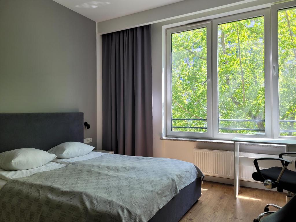 a bedroom with a bed and two large windows at Chopin Apartments Expo in Warsaw