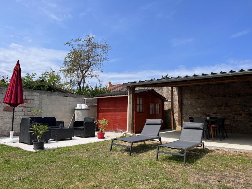eine Terrasse mit Stühlen, einem Tisch und einem roten Regenschirm in der Unterkunft Maison Saint Michel in Cabourg