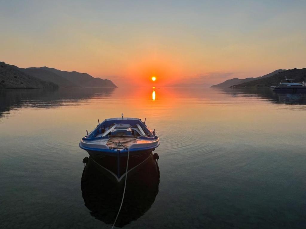 a boat in the water with the sunset in the background at Symi . VILLA CALME (Sur la Mer). in Symi