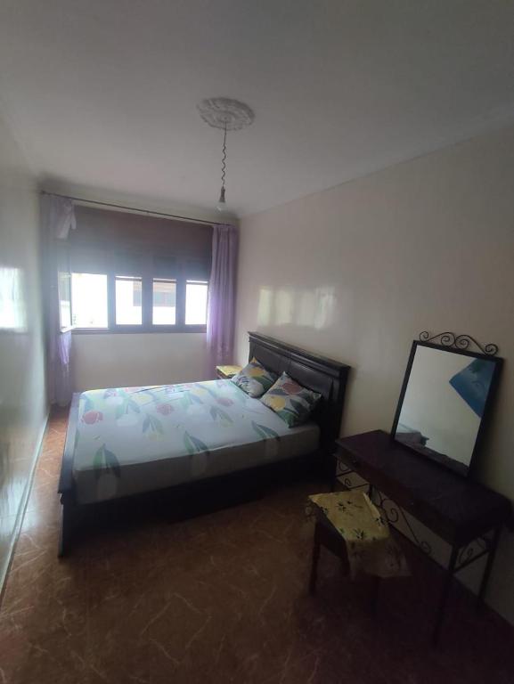 1 dormitorio con cama, espejo y mesa en Maison en lieu calme en El Jadida