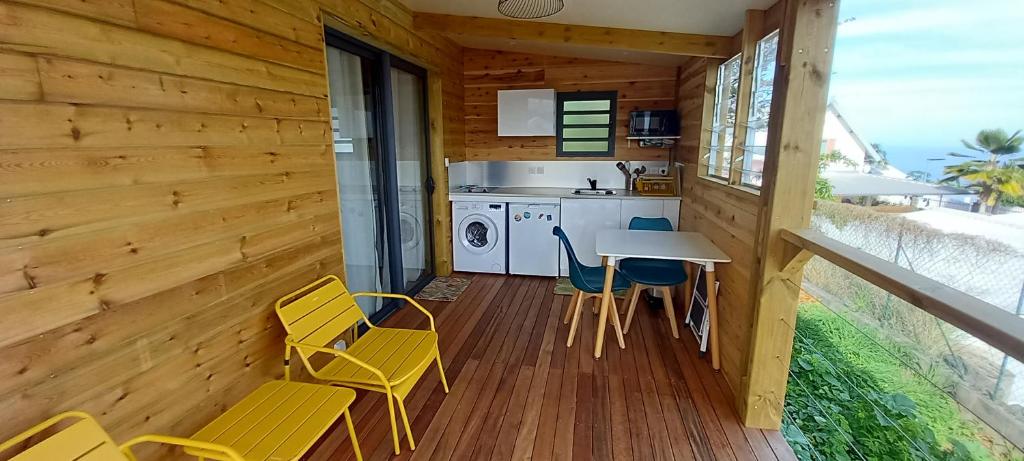 eine Küche mit gelben Stühlen und einem Tisch auf einer Terrasse in der Unterkunft Bungalow de Coco in Saint-Paul